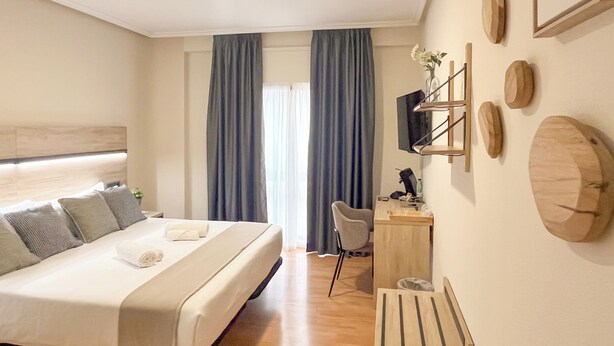 A modern hotel room with a large bed, a desk, a chair, and a TV on the wall. - VTZ Hotel El Príncipe (Zaragoza)