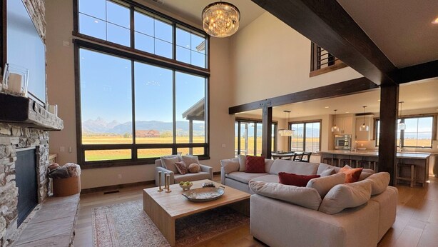 Un salón amplio con chimenea, ventanas grandes y vistas a montañas.