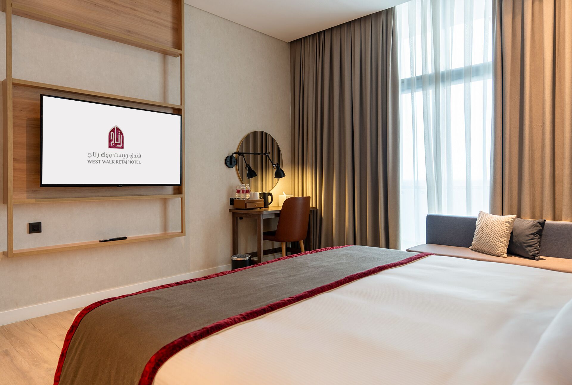 A hotel room with a bed, a desk with a chair, a TV mounted on the wall, and a large window with curtains.