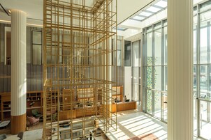 Un interior moderno con una estructura de celosía de madera, ventanas amplias y un mostrador de recepción.