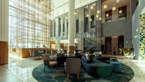Eine großzügige Lobby mit modernem Design, ausgestattet mit einer Sitzecke, Sofas und Sesseln, einem großzügigen, offenen Bereich und einer hohen Decke mit Pendelleuchten.