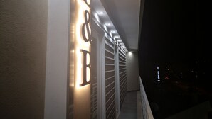 A hallway with illuminated wall letters and a staircase with a railing. - Living (Casoria)