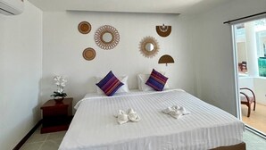 A modern bedroom with a large bed, decorative wall art, and a view of the outdoors. - Gee Resort (Koh Tao)