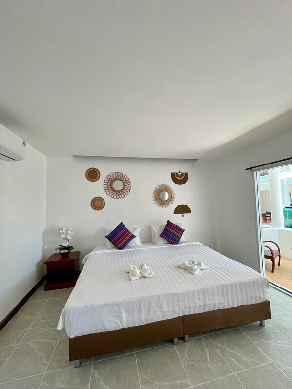 A modern bedroom with a large bed, decorative wall art, and a view of the outdoors.