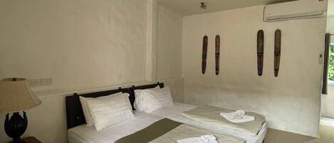 A bedroom with a bed, a ceiling fan, an air conditioning unit, and skis on the wall.