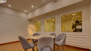 Un comedor con una mesa redonda y cuatro sillas, suelo de madera y apliques decorativos.