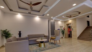 Una sala de estar moderna con un sofá, un sillón, una mesa de centro, una escalera y una puerta que da a otra zona.