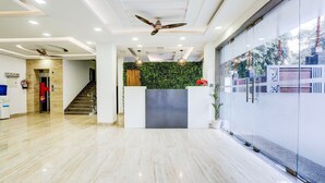 Un vestíbulo moderno con suelo de mármol, un mostrador de recepción, una escalera y un muro de cristal con vistas.