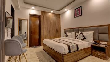 Un dormitorio moderno con una cama grande, un ventilador de techo, un armario de madera y una mesita de noche pequeña.