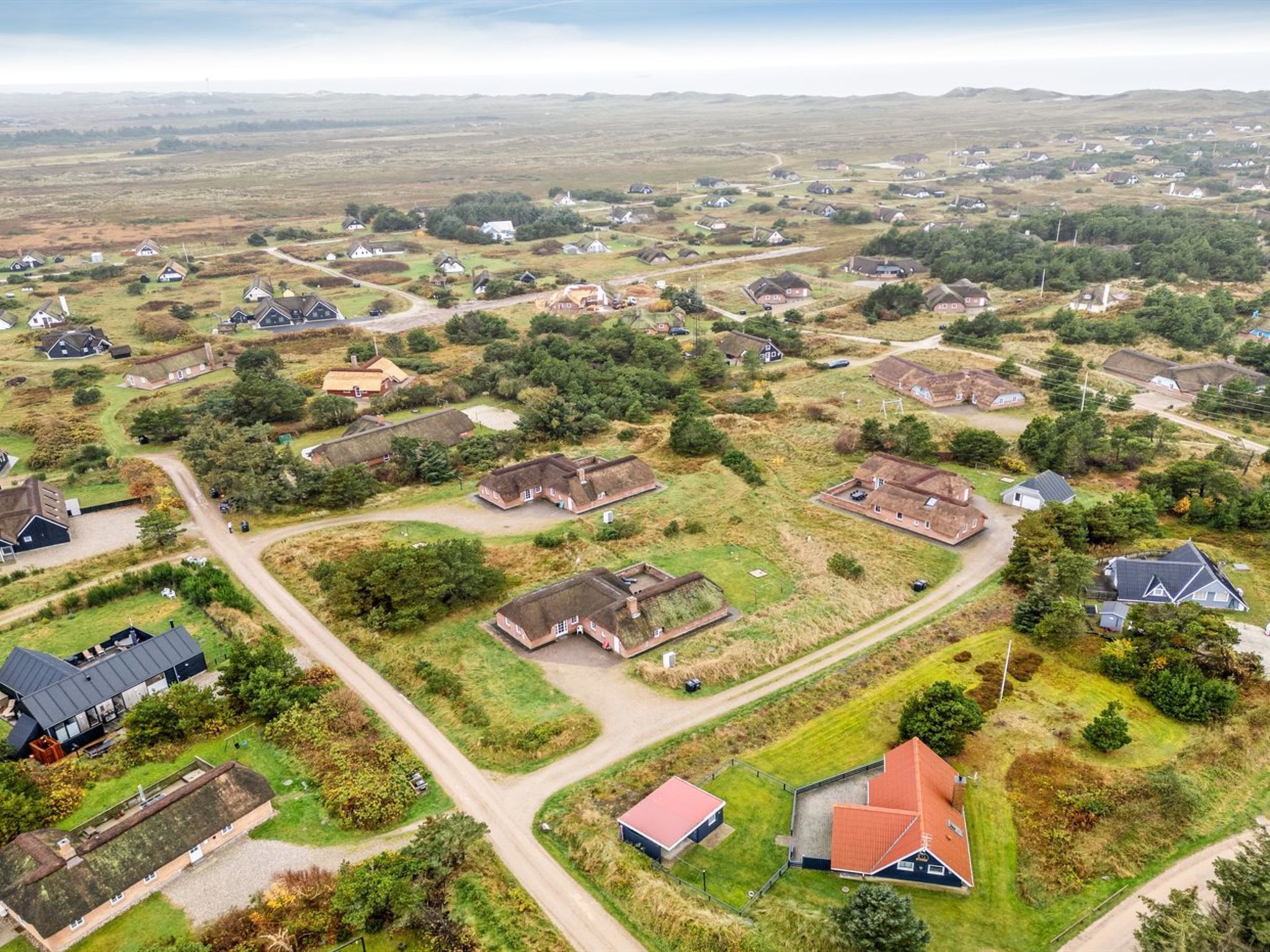 An aerial view of a rural residential area with scattered houses, roads, and green spaces.