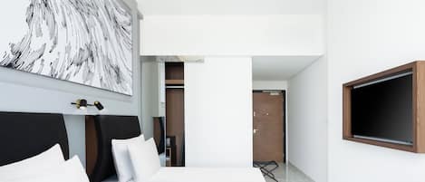 Una camera d'albergo moderna con un letto grande, una TV a parete e un quadro sopra il letto.