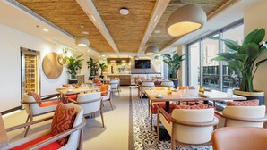 A modern restaurant with wooden ceiling beams, large windows, and indoor plants. - Holiday Inn Dubai Jumeirah Village Circle by IHG (Dubai)