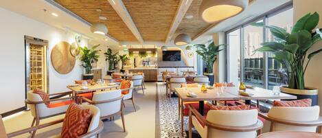 Um restaurante moderno com vigas de madeira no teto, janelas amplas e plantas dentro.