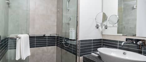 A modern bathroom with a glass-enclosed shower, a freestanding sink, and two wall-mounted mirrors.