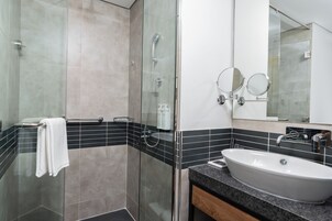 A modern bathroom with a glass-enclosed shower, a freestanding sink, and two wall-mounted mirrors.