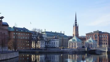 A historic cityscape with a prominent church tower, a bridge, and a calm river reflecting the buildings.