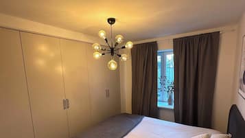 A bedroom with a large bed, a ceiling light fixture, and a window with curtains.