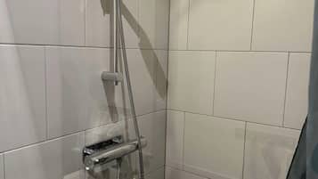 A shower with a handheld showerhead and a handheld shower attachment.