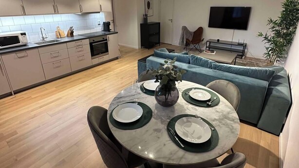 Een moderne keuken met een eethoek, een flatscreen televisie en een bank.