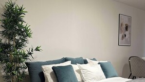 Een moderne slaapkamer met een bed, een kamerplant en een stoel.