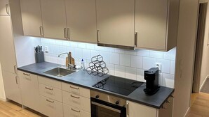 Een moderne keuken met roestvrijstalen kastjes, een zwart aanrecht, een inbouwoven en een koffiezetapparaat.