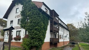 A two-story building with a white facade and brown trim, featuring a balcony and a sign that reads "Castles." - Gasthof Zum schwarzen Roß (Zeitlofs)