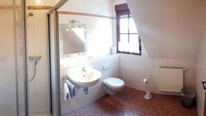 A bathroom with a shower, sink, toilet, and a window providing natural light. - Gasthof Zum schwarzen Roß (Zeitlofs)