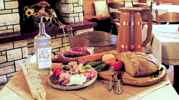 A table with a variety of food items, a bottle, and a copper mug. - Gasthof Zum schwarzen Roß (Zeitlofs)