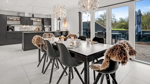 A modern kitchen with a central island, black chairs, and a dining table set for six. - "Elisaveta" - 400m to the fjord by Interhome (Vemb)