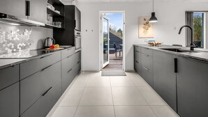 A modern kitchen with grey cabinetry, a tiled floor, and a view to the outside. - "Elisaveta" - 400m to the fjord by Interhome (Vemb)