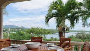 Uma área de refeições com uma mesa posta para quatro pessoas, com vista para uma paisagem deslumbrante de um lago e montanhas.