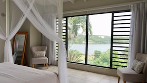 Quarto com uma janela grande, uma cama, duas cadeiras e um espelho.