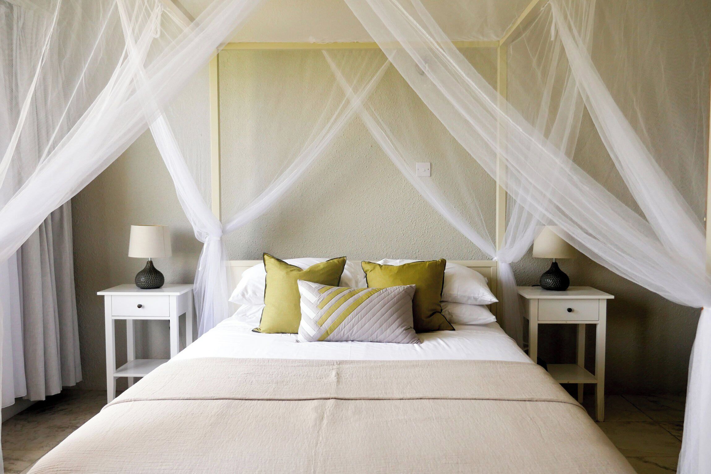 A bed with a canopy, two bedside tables with lamps, and pillows.
