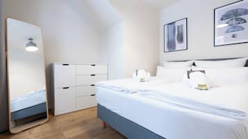Een moderne slaapkamer met een bed, een kledingkast, een spiegel en twee ingelijste foto’s aan de muur.
