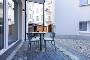 Une cour avec une table et des chaises, une porte en bois et, au fond, un bâtiment doté de balcons.