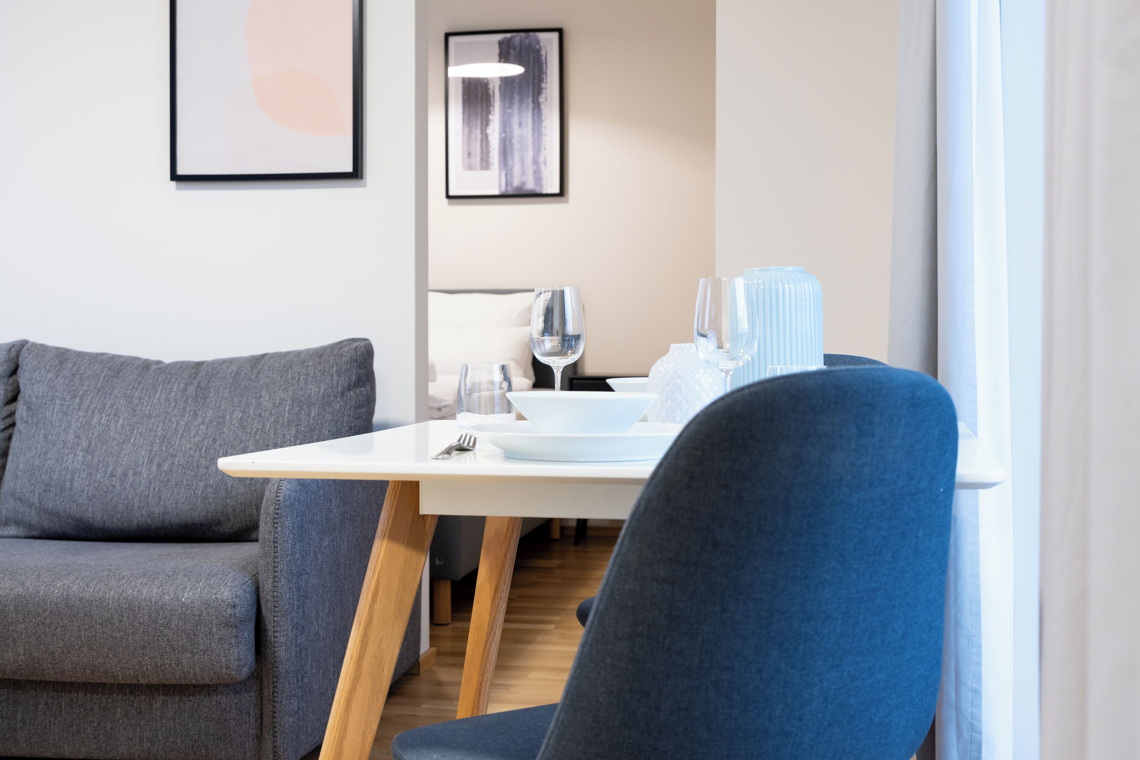 Uma sala de jantar moderna com uma mesa branca, cadeiras cinzas e azuis e decoração minimalista.