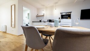 A modern kitchen with a dining area, wooden flooring, and a flat-screen TV mounted on the wall. - BRIGHT Leipzig Zentrum-West Stadium (Leipzig)