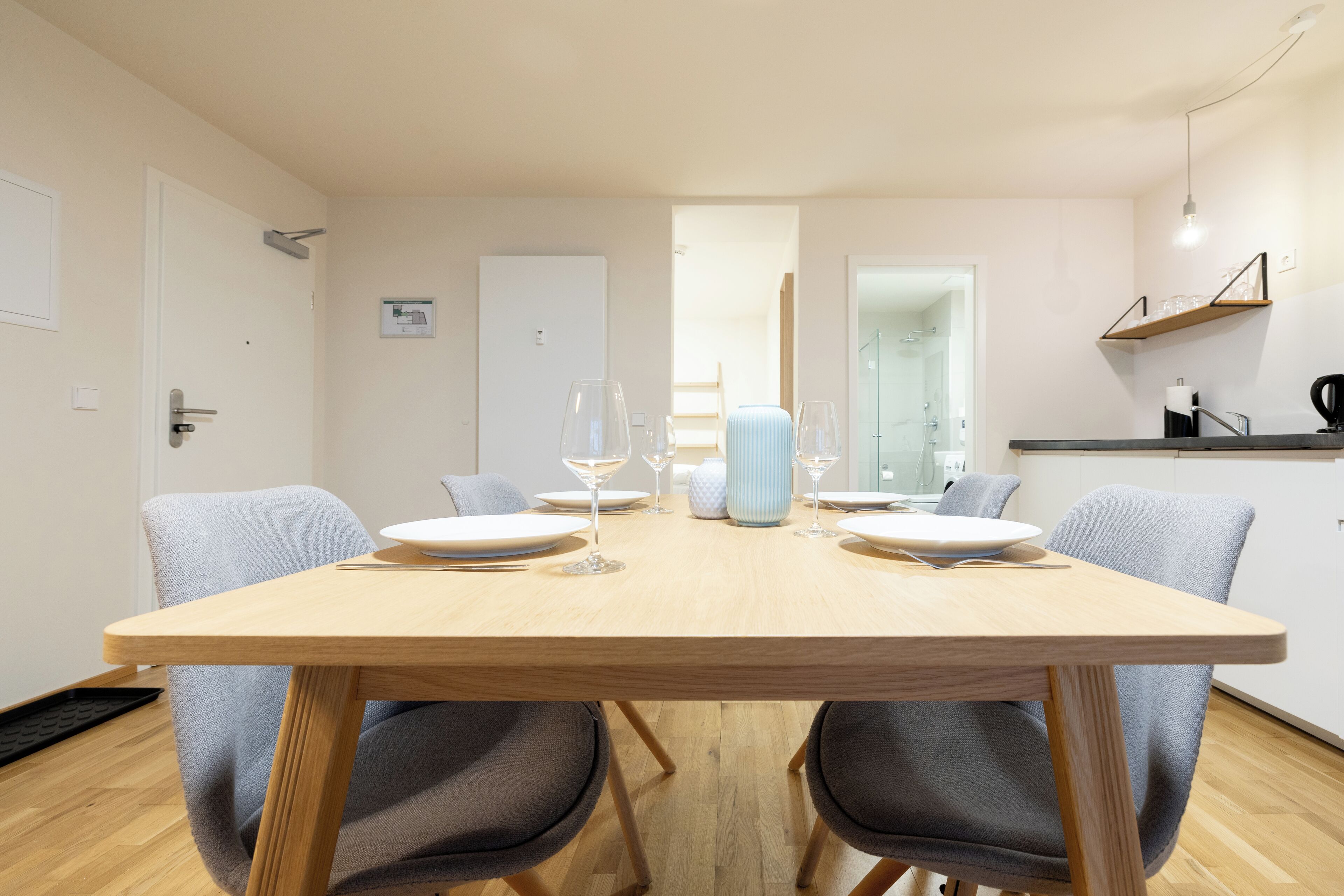 Un espace repas moderne avec une table en bois dressée pour quatre personnes, entourée de chaises grises.