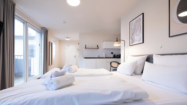A hotel room with two beds, a kitchenette, and a balcony. - BRIGHT Leipzig Zentrum-West Stadium (Leipzig)