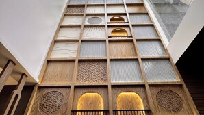 Un intérieur à plusieurs niveaux, avec des lambris en bois et des motifs géométriques, agrémenté d’une lucarne et offrant une vue sur le ciel.