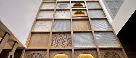 Un interior de varios niveles con paneles de madera y patrones geométricos, que cuenta con un tragaluz y vistas al cielo.