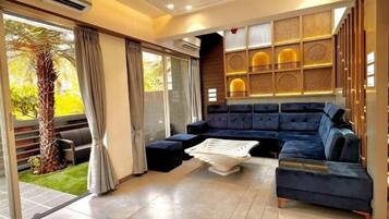 Un salon moderne avec un canapé bleu foncé, une table basse blanche et un ventilateur de plafond.
