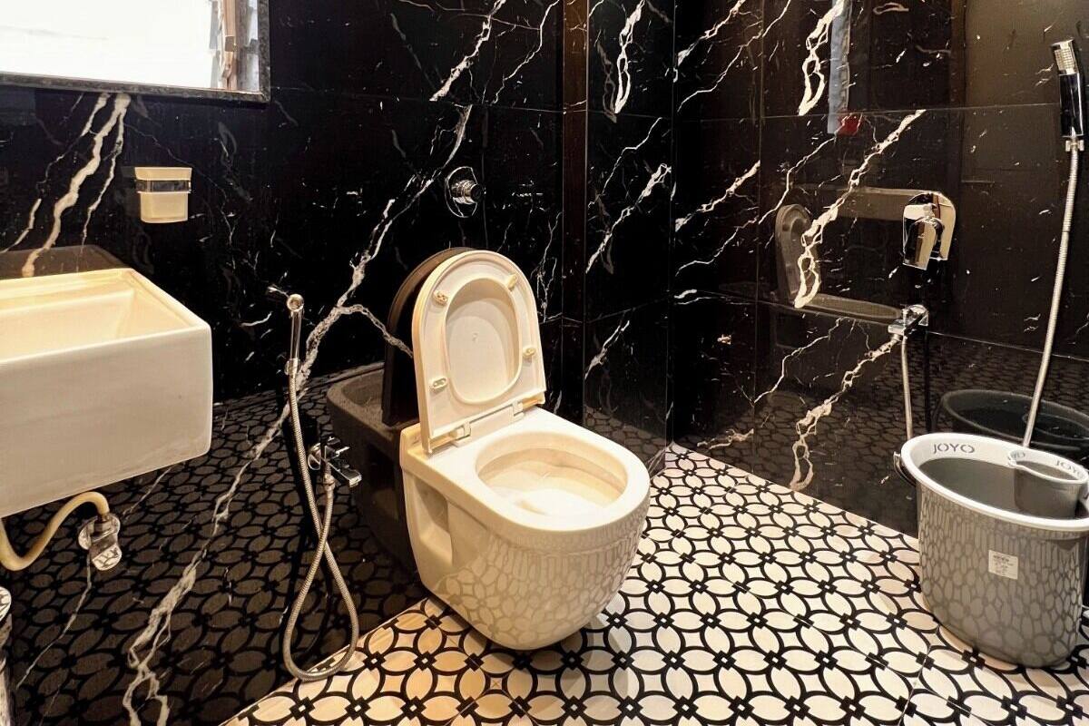 Une salle de bain moderne avec un sol en marbre, des toilettes blanches, un lavabo et un espace douche.