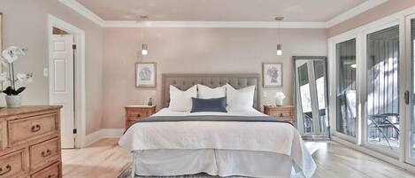 Une chambre avec un grand lit, des tables de chevet, une commode et une vue sur l’extérieur grâce à une porte-fenêtre coulissante.