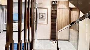 Un intérieur d’hôtel moderne avec un escalier menant à un deuxième étage, une œuvre d’art encadrée au mur et un motif décoratif en panneaux de bois sur le mur.