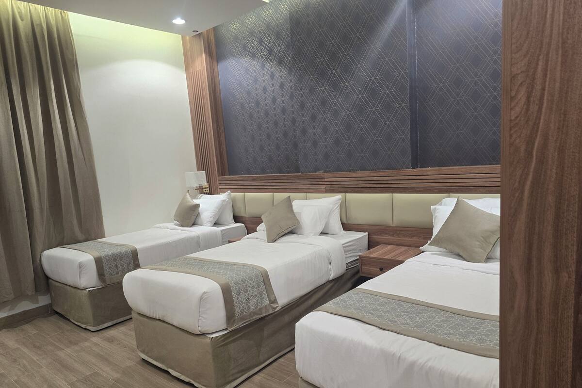 A hotel room with two single beds, a large window, and a wooden headboard.