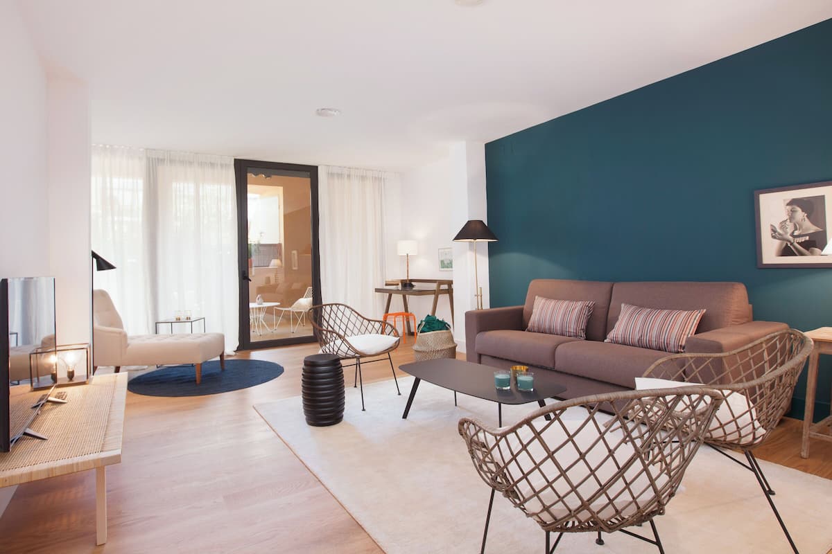 Una sala moderna con sofá, sillones, una mesa de centro y televisión.