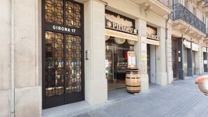 A building facade with storefronts, including a visible door labeled "GIRONA 17" and a sign for "PIRIEU CARNISSERIA & BOTIGA." - En Casa de Girona 17 (Barcelona)