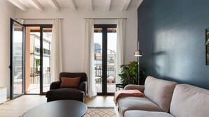 A modern living room with a sofa, a coffee table, and a view of the outside balcony. - En Casa de Girona 17 (Barcelona)