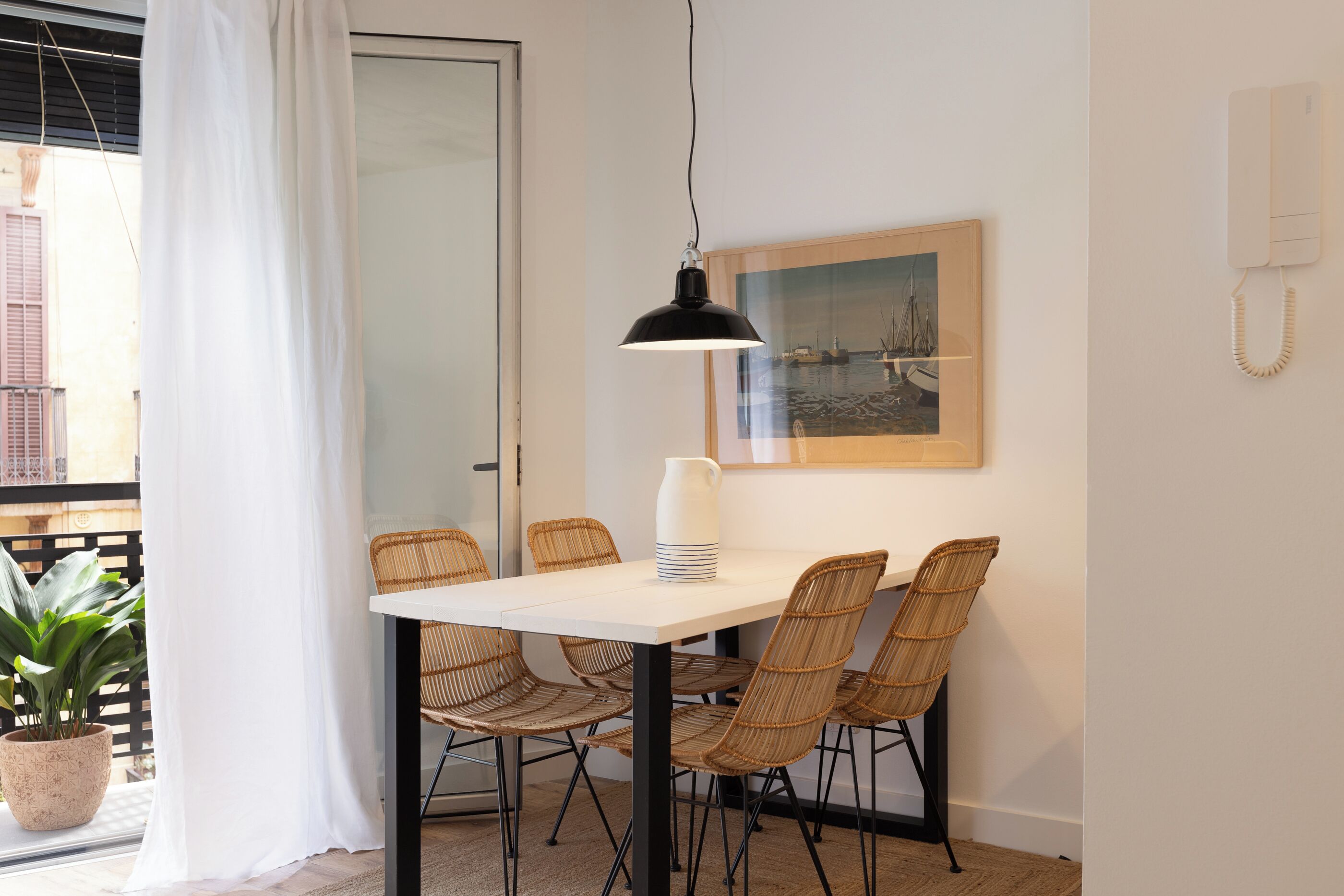 Ein Essbereich mit Tisch, Stühlen, einer Hängelampe, einem gerahmten Bild und einem Telefon an der Wand.